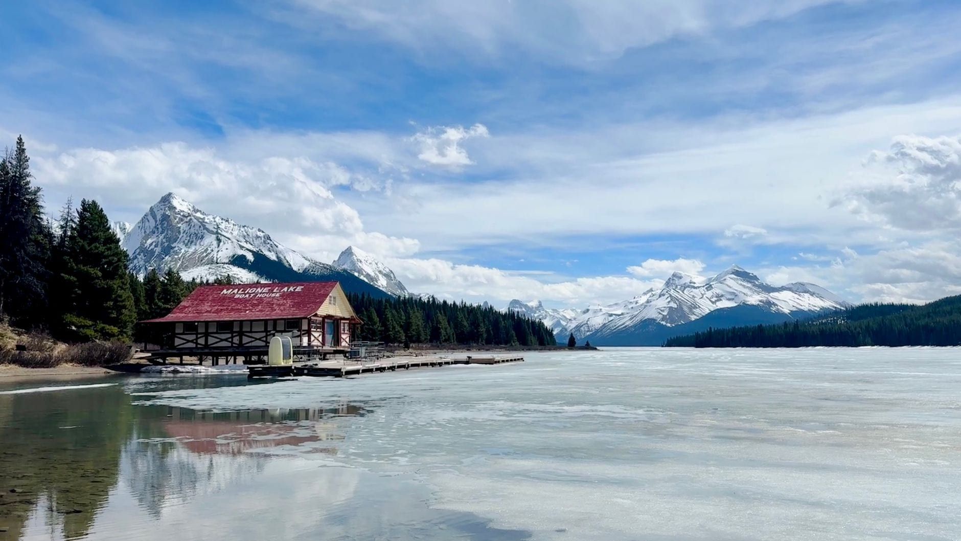 Maligne Lake Boat House sits along the partially frozen lakeshore backed by snow-capped mountains in Jasper National Park.