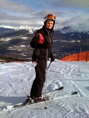 A skier standing on a snow-covered slope at Marmot Basin ski resort with snowcapped mountain ranges in Jasper National Park.