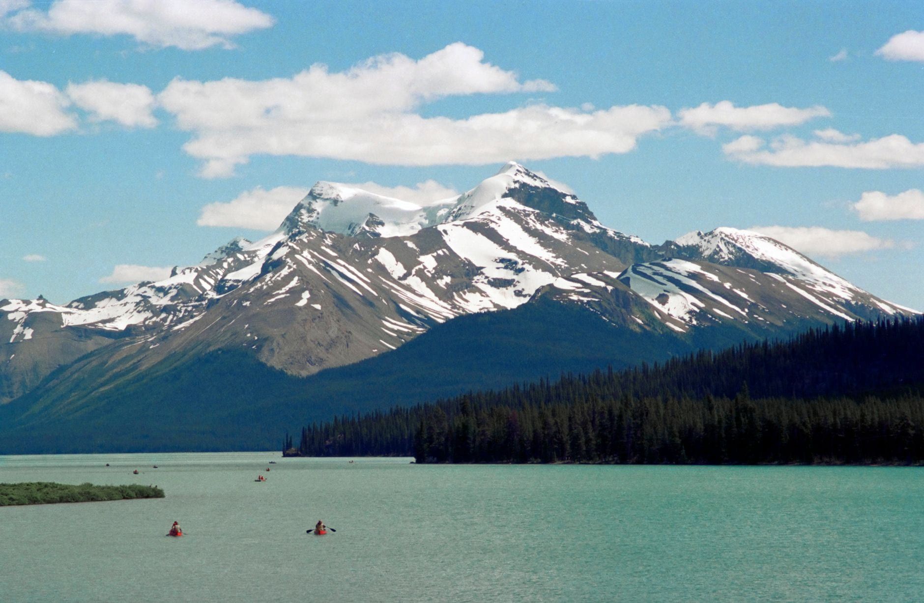 Kanus paddeln über das türkisfarbene Wasser des Maligne Lake, umrahmt von immergrünen Wäldern und schneegestreiften Berggipfeln im Jasper National Park.