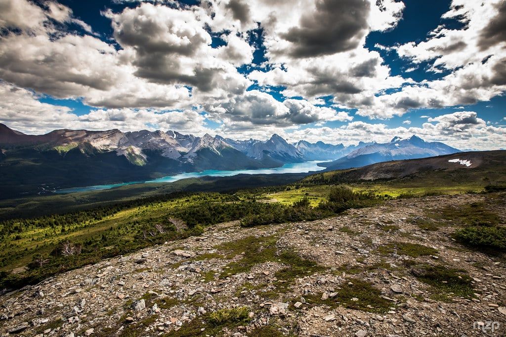 Panoramic view from the rocky ridge of Bald Hills looking out over Maligne Lake and towering mountain peaks in Jasper National Park.