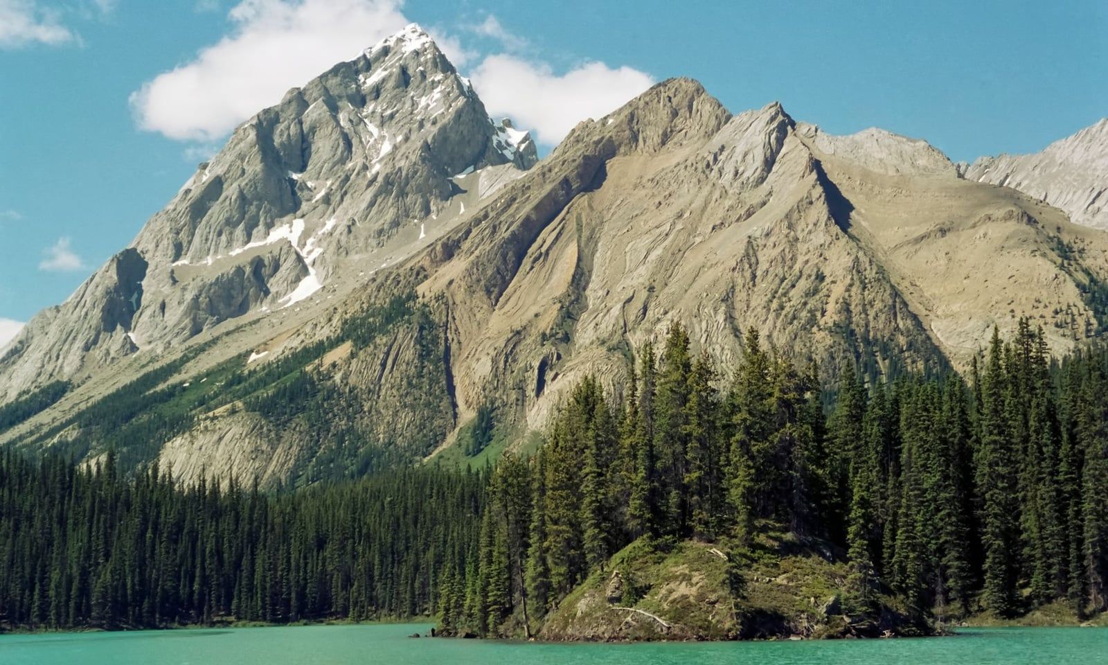 Conifer trees stand on Spirit Island surrounded by the turquoise water of Maligne Lake below Samson Peak in Jasper National Park.