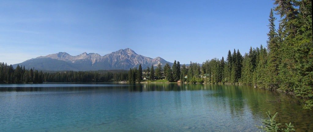 Turkoois water van Lac Beauvert omlijst door naaldbossen en ruige bergen in Jasper National Park.